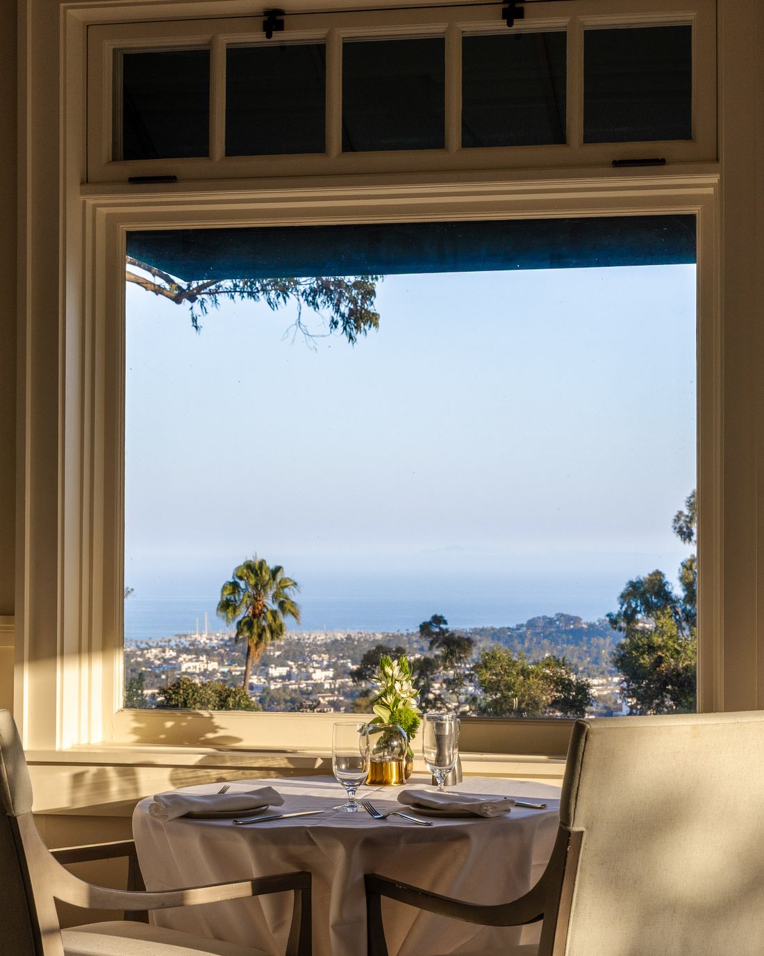 A table set by an open window overlooking the coast